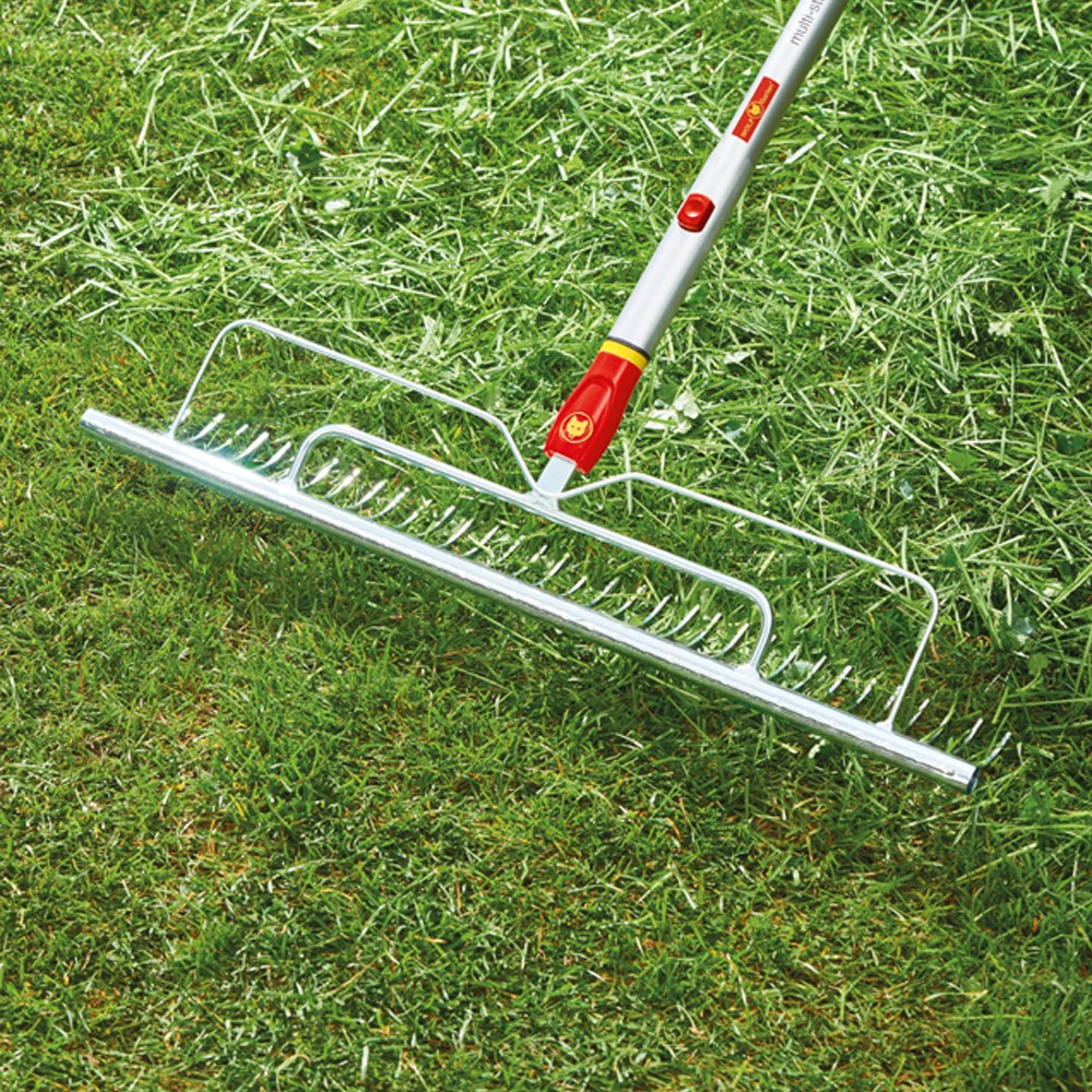 WOLF-Garten UHM Multi-Change® Longspan Rake with red and yellow 58cm head and curved tines, displayed raking a green lawn.